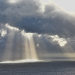 Low angle shot of the sun shining through the clouds over the beautiful ocean